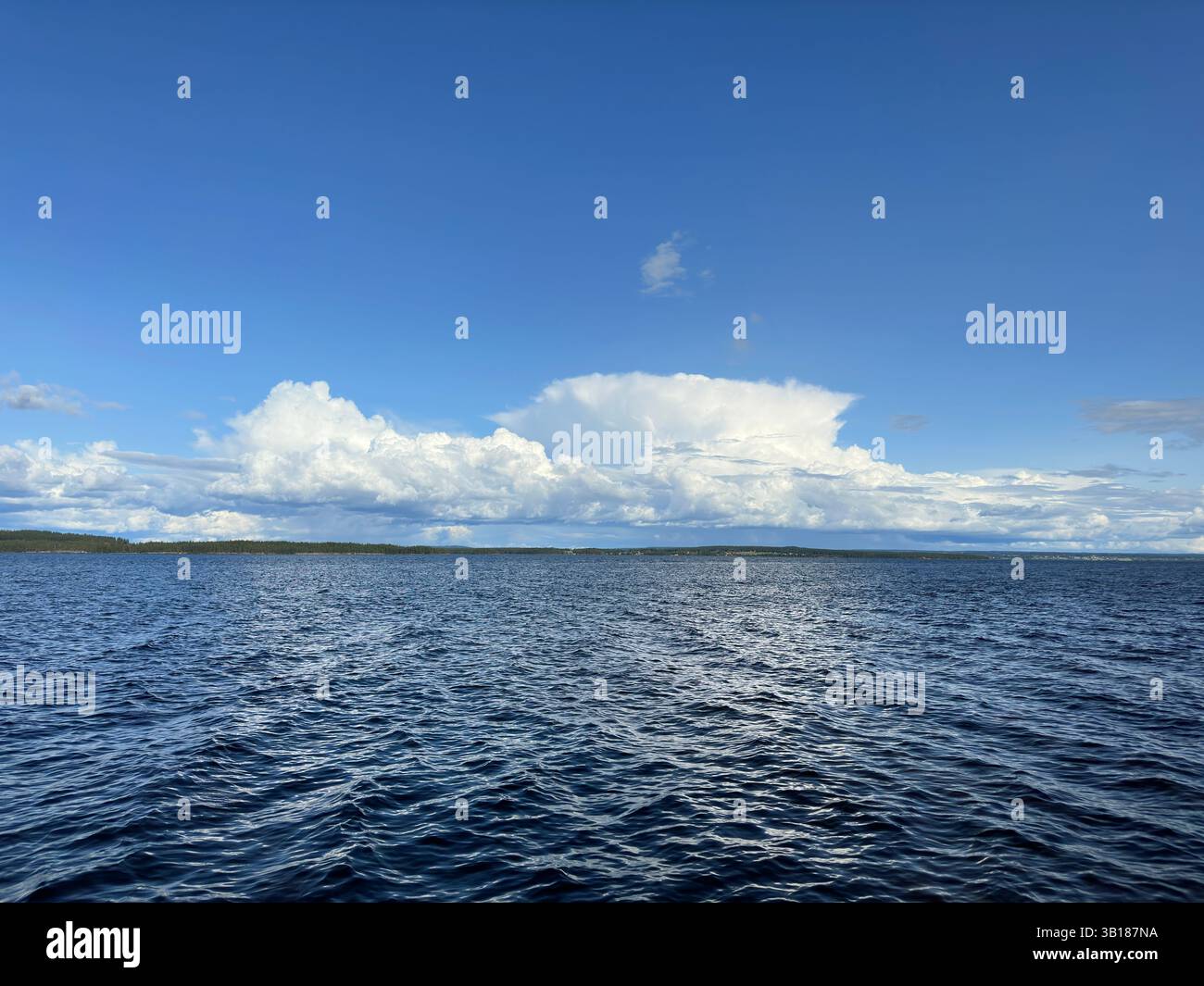 Un bellissimo paesaggio marino caratterizzato da un vasto oceano sotto un cielo azzurro limpido con soffici nuvole bianche. - Immagine stock catturata con smartphone