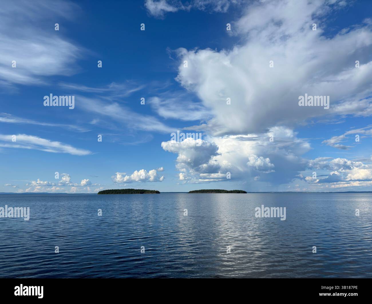 Vista di un lago tranquillo con isole sotto un cielo vibrante e parzialmente nuvoloso in Svezia. - Immagine stock catturata con smartphone