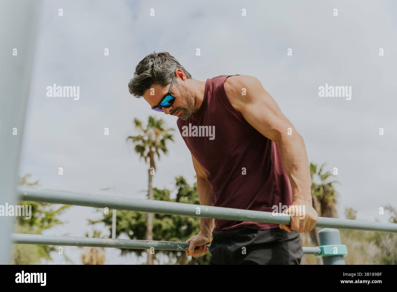 Un uomo sta facendo immersioni con i bar e si sta allenando all'aperto in un luogo tropicale. Foto Stock