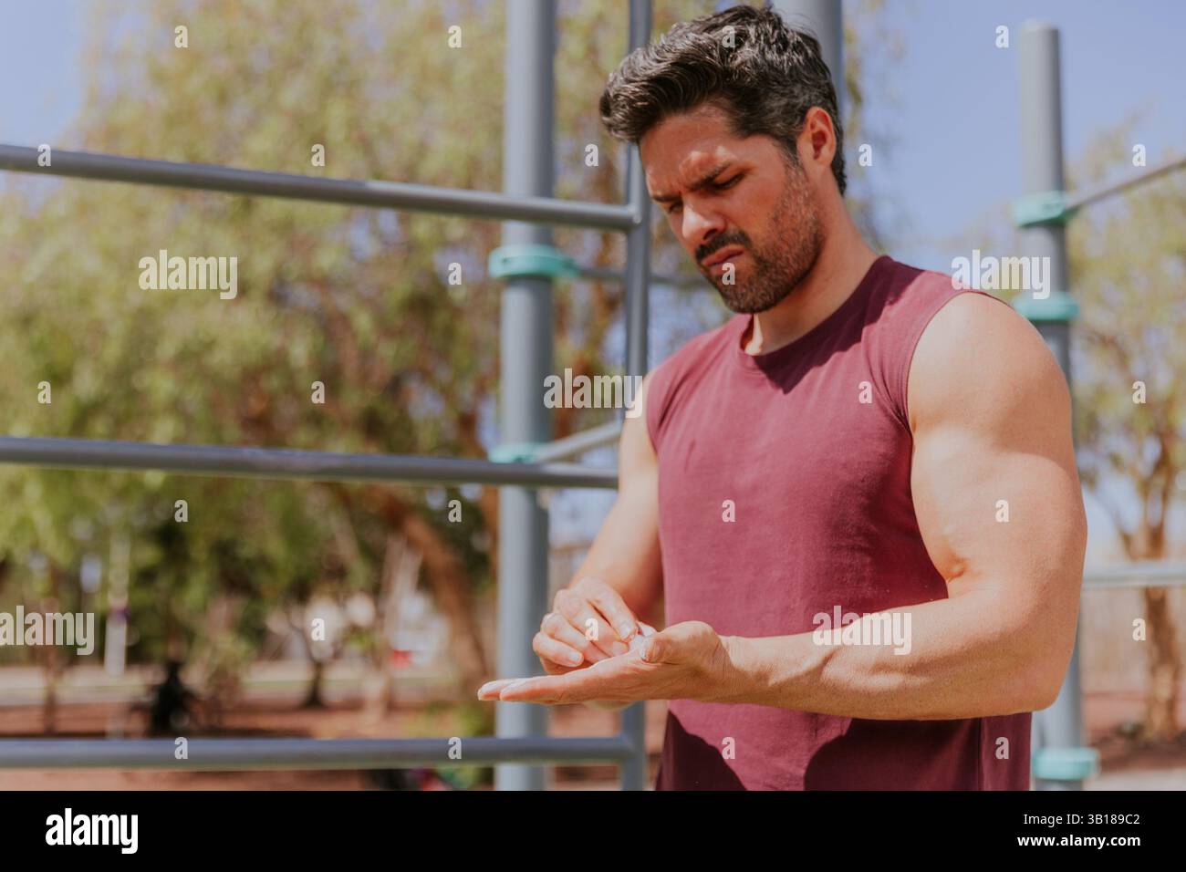 Un uomo caucasico in forma sui quarant'anni sta applicando polvere di magnesio sulle mani prima di allenarsi. Foto Stock