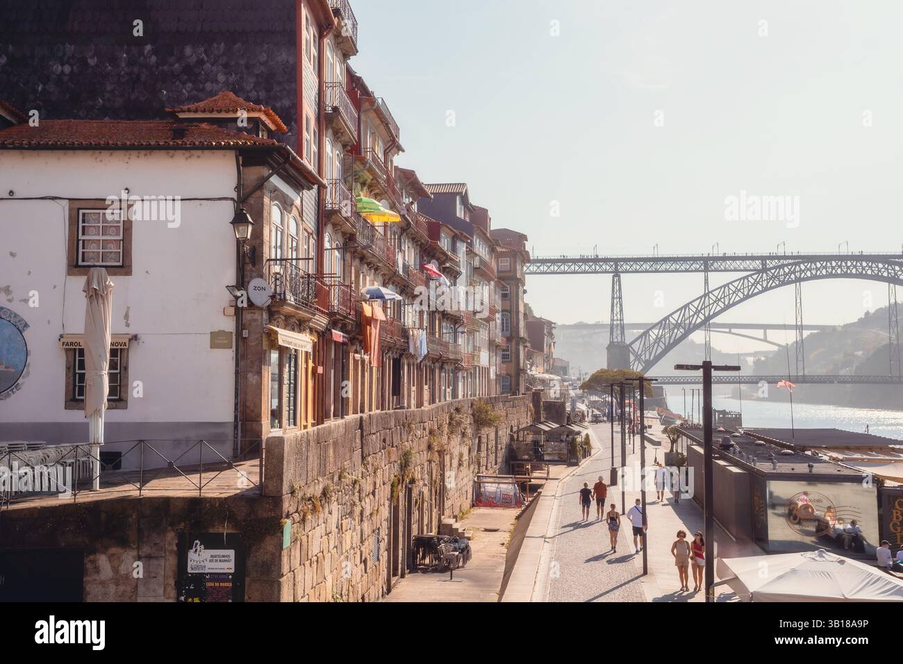 Piazza Ribeira a Porto, Portogallo, con colorati edifici storici, vivace atmosfera sul lungomare e caffetterie all'aperto lungo il fiume Douro. Foto Stock