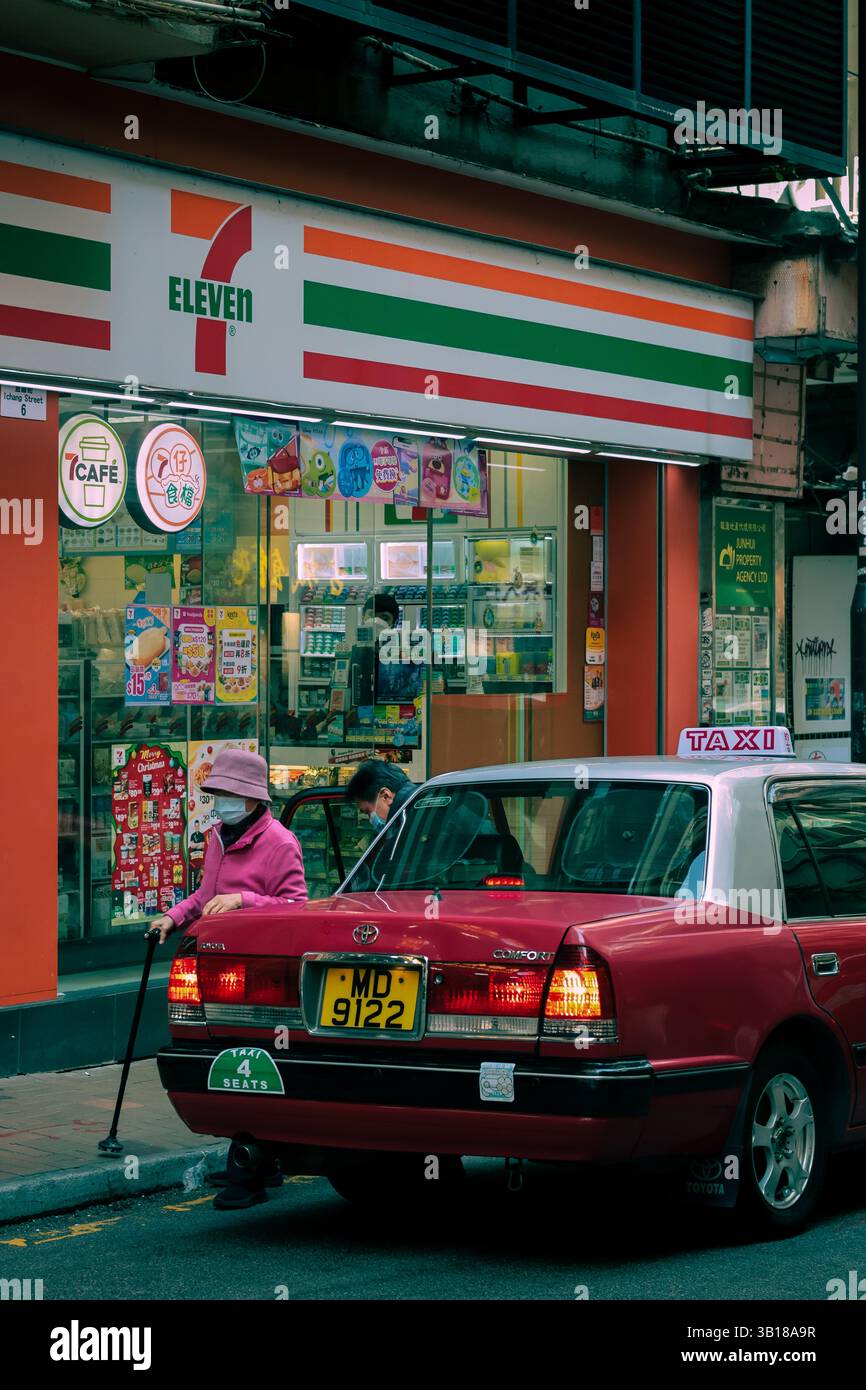 Una donna anziana esce da un taxi a Hong Kong, atmosfera vintage. Foto Stock