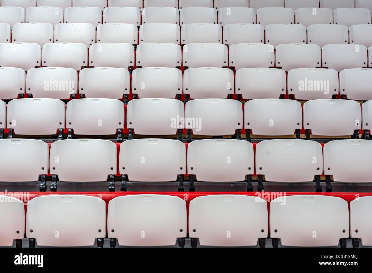 Immagine ravvicinata dei sedili pieghevoli in plastica rossa e bianca in una palestra interna. Foto Stock