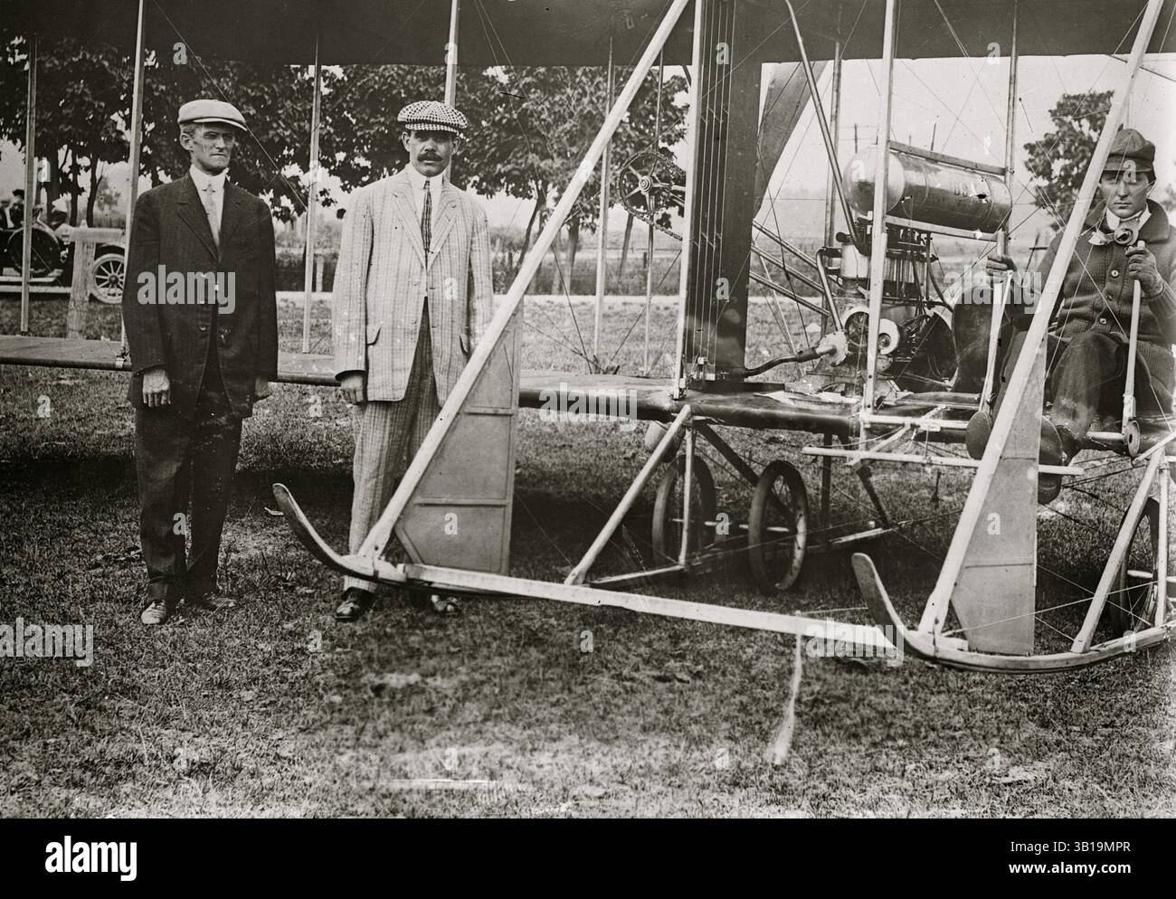 6 giugno 1912 - Stati Uniti - (L-R) C.P. HENDERSON, BOB FOWLER e ROLAND GARROS al bastone di un primo biplano durante una visita negli Stati Uniti nel 1912. Garros (Parigi, 6 ottobre 1888 – Parigi, 5 ottobre 1918) è stato un aviatore e pilota di aerei da caccia francese durante la prima guerra mondiale. Garros è nato a Saint-Denis, Reunion e ha studiato all'HEC di Parigi. Garros iniziò la sua carriera nel 1909 volando sul monoplano Demoiselle di Santos-Dumont, un aereo che volava bene solo con un piccolo pilota leggero. Nel 1911 Garros si laureò a pilotare monoplani Bleriot ed entrò in una serie di gare aeree europee con questo tipo di mac Foto Stock