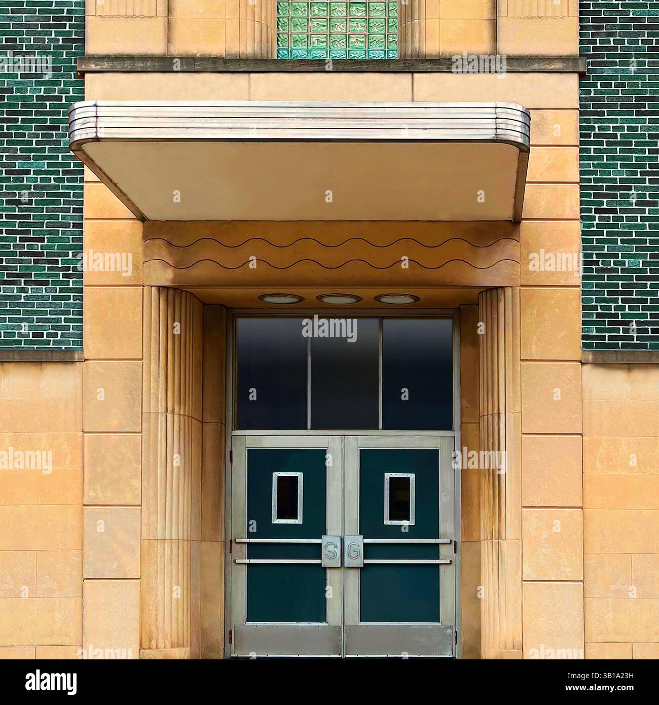 Ingresso in stile moderno con doppie porte verdi, dettagli in vetro, baldacchino scolpito e facciata geometrica in pietra a Chicago Foto Stock