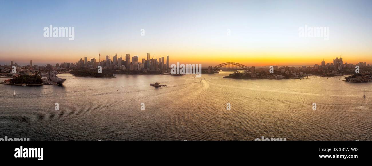 Panoramico panorama aereo sul porto di Sydney verso i principali monumenti architettonici dello skyline della città sulle rive al tramonto. Foto Stock