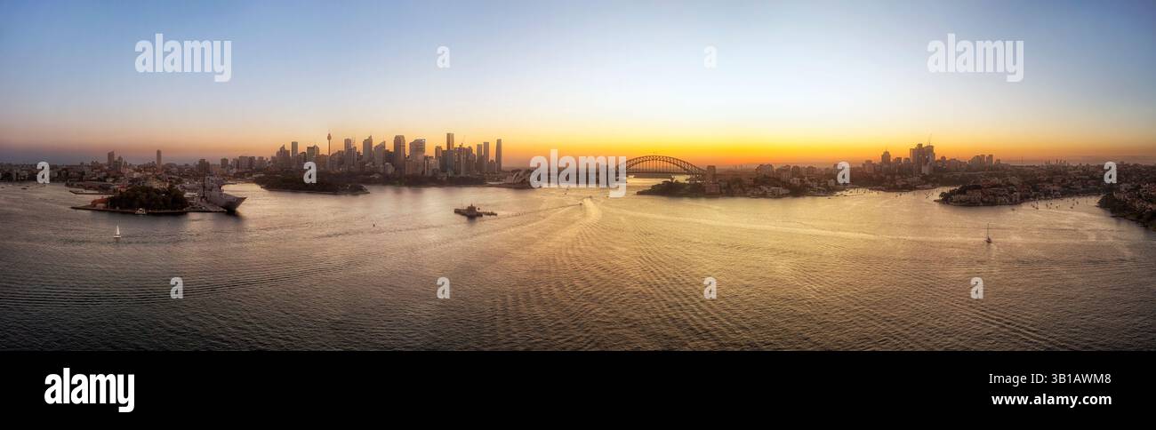 Ampio panorama aereo sul porto di Sydney fino ai principali monumenti architettonici dello skyline della città sulle rive al tramonto. Foto Stock