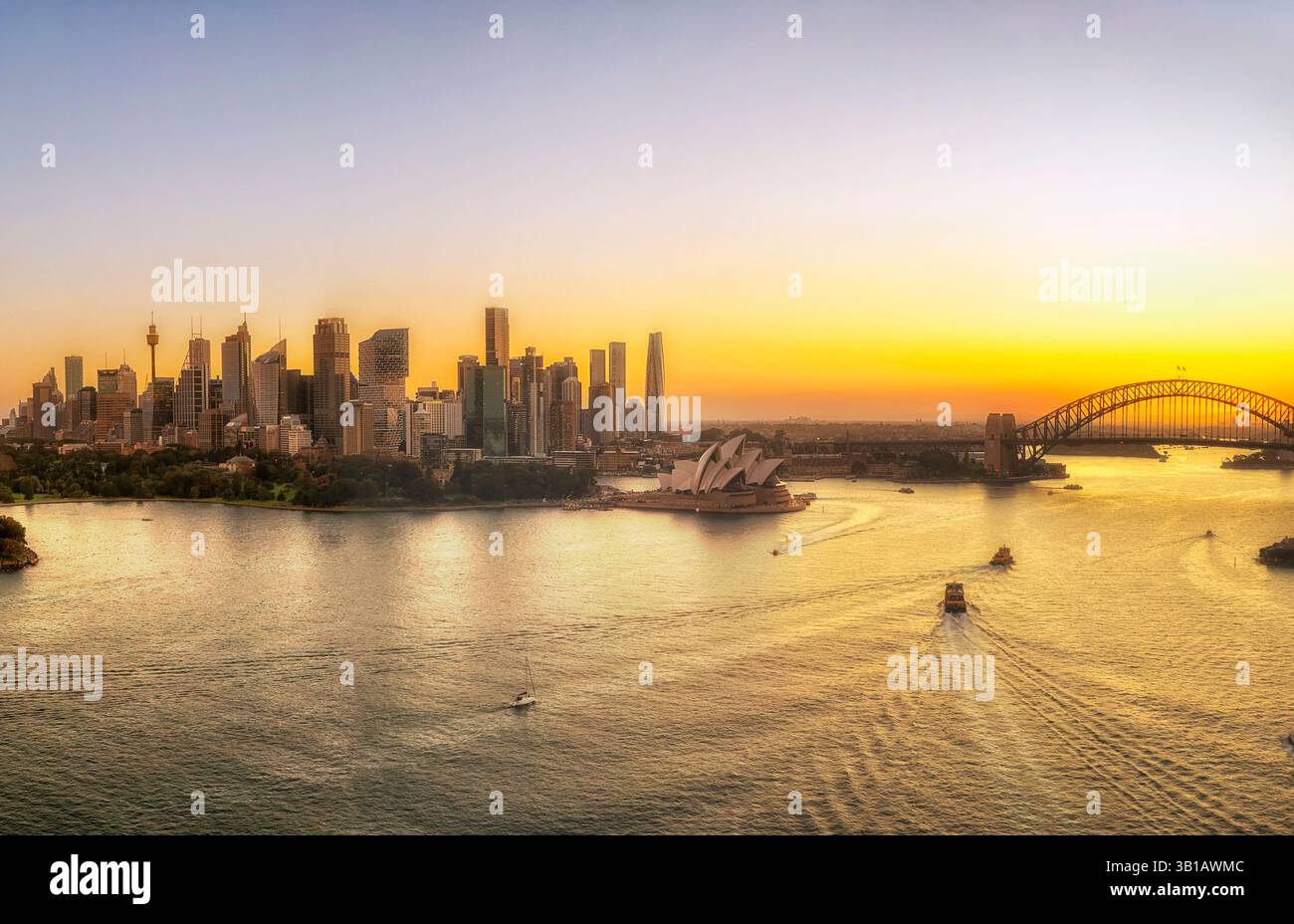 Vista aerea alla luce del tramonto dell'ora d'oro sul paesaggio cittadino di Sydney che si riflette nelle acque del porto. Foto Stock