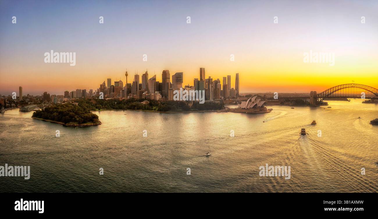 Luce del tramonto dell'ora d'oro sul paesaggio urbano di Sydney che si riflette nelle acque del porto - vista aerea. Foto Stock