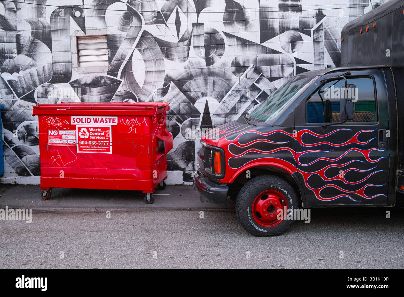 Un murale e un vicolo a Mount Pleasant, al largo di Main Street, Vancouver, British Columbia, con un bidone della spazzatura e un furgone vintage con un lavoro di verniciatura ardente. Foto Stock