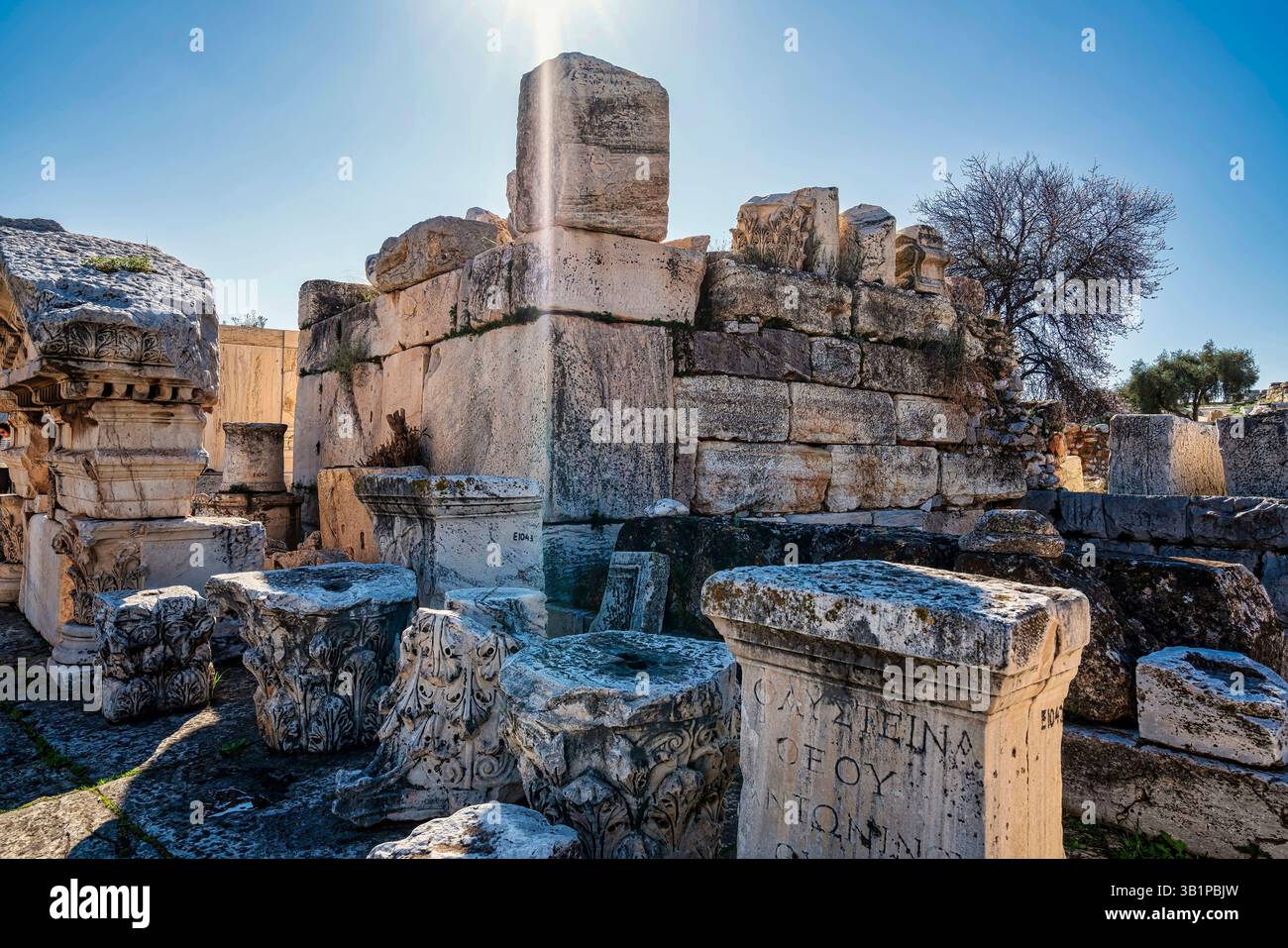Blocchi di marmo, basi incise e capitelli scolpiti dalle rovine di Telesterion a Eleusi, con la luce del sole che evoca un'antica eredità rituale. Foto Stock