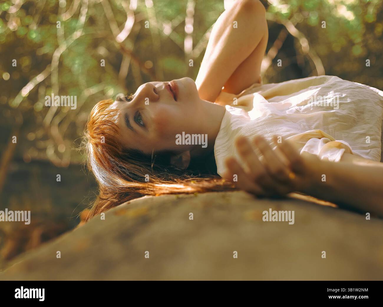 Una donna appoggiata contro la cavità di un albero alto nella foresta Foto Stock