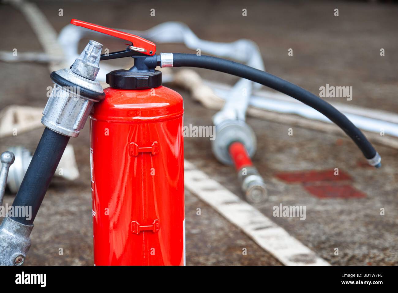 Cilindro dell'estintore rosso con tubi flessibili antincendio non avvolti. Foto Stock