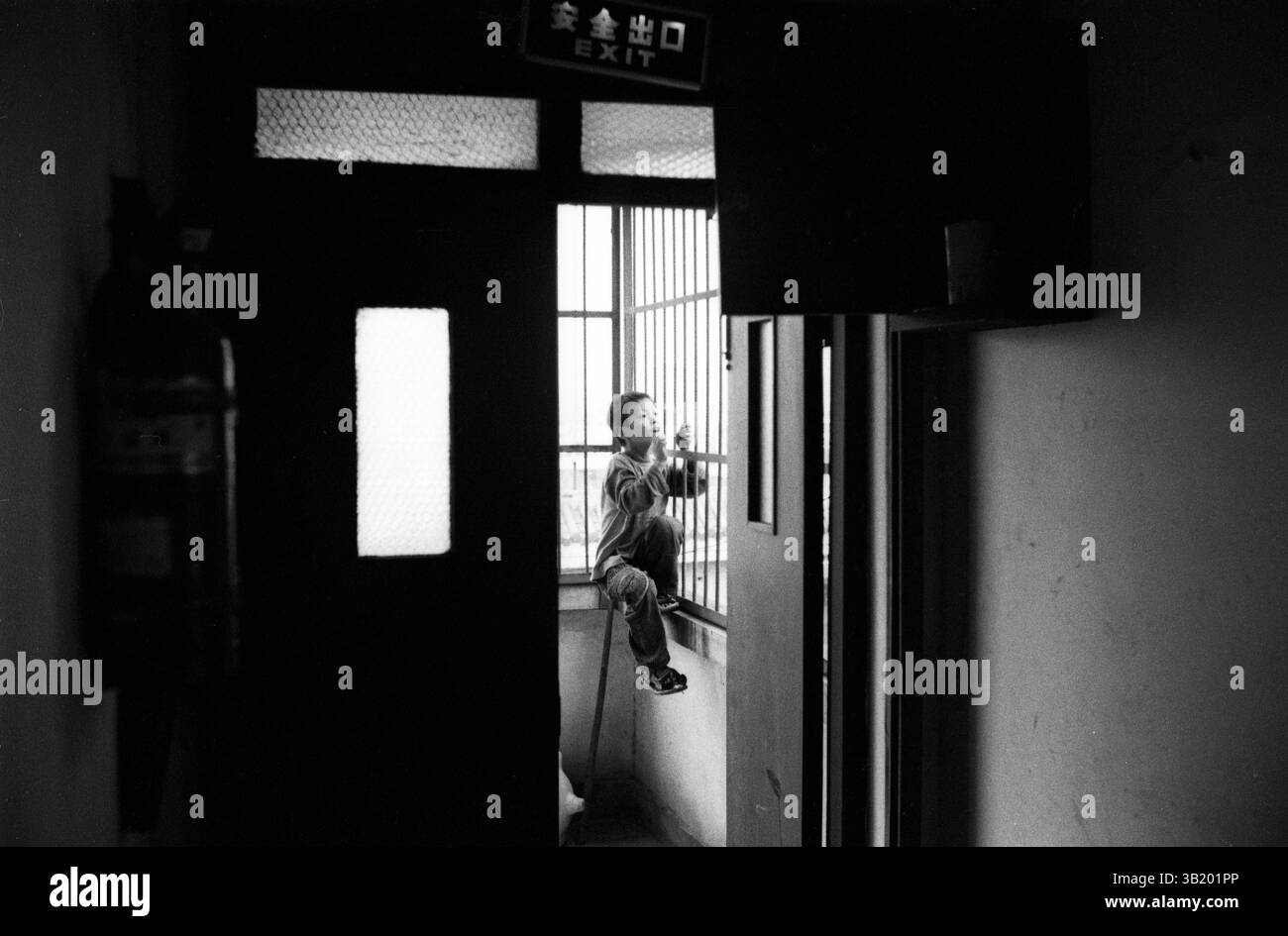 Boy Climbing Window Bar in un edificio per uffici cinese degli anni '2010 Foto Stock