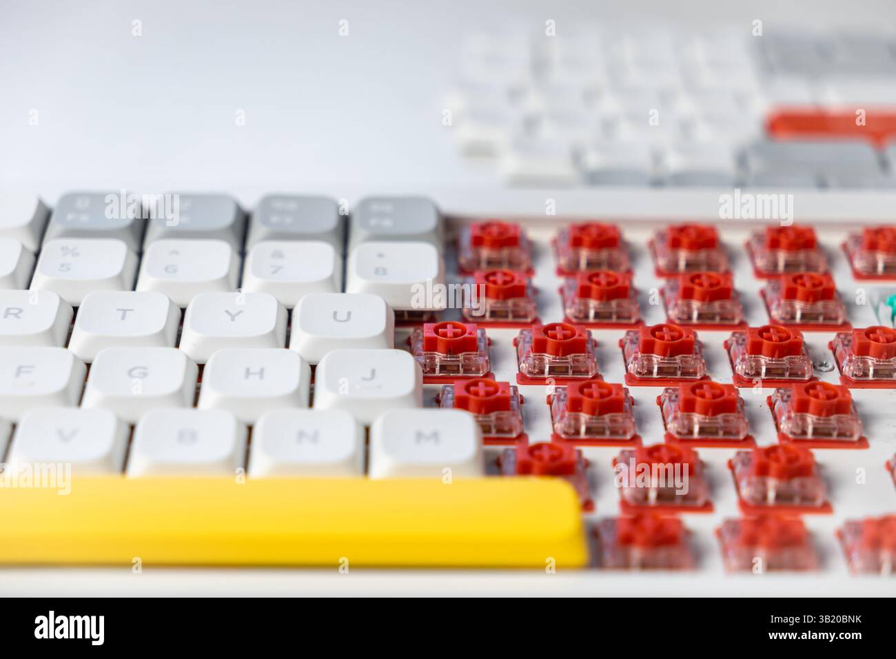 Foto macro dettagliata di una tastiera meccanica parzialmente disassemblata con interruttori rossi visibili, con design dell'interruttore tattile, modifica fai da te e. Foto Stock