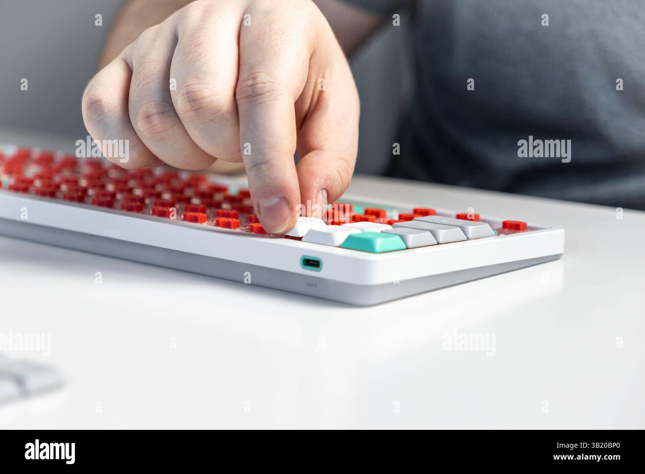 Primo piano di una persona che fissa un cappuccio bianco su un interruttore meccanico rosso durante l'assemblaggio della tastiera, sottolineando la personalizzazione, il feedback tattile e. Foto Stock