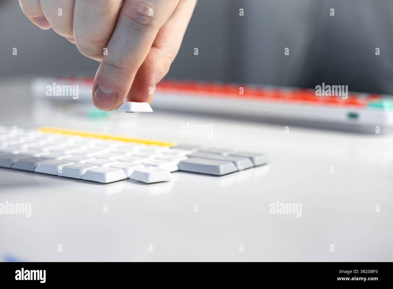 Primo piano di una mano che solleva un tasto da una tastiera compatta con un layout pulito, evidenziando l'interazione dell'utente, la sostituzione dell'interruttore, la manutenzione tecnica, Foto Stock