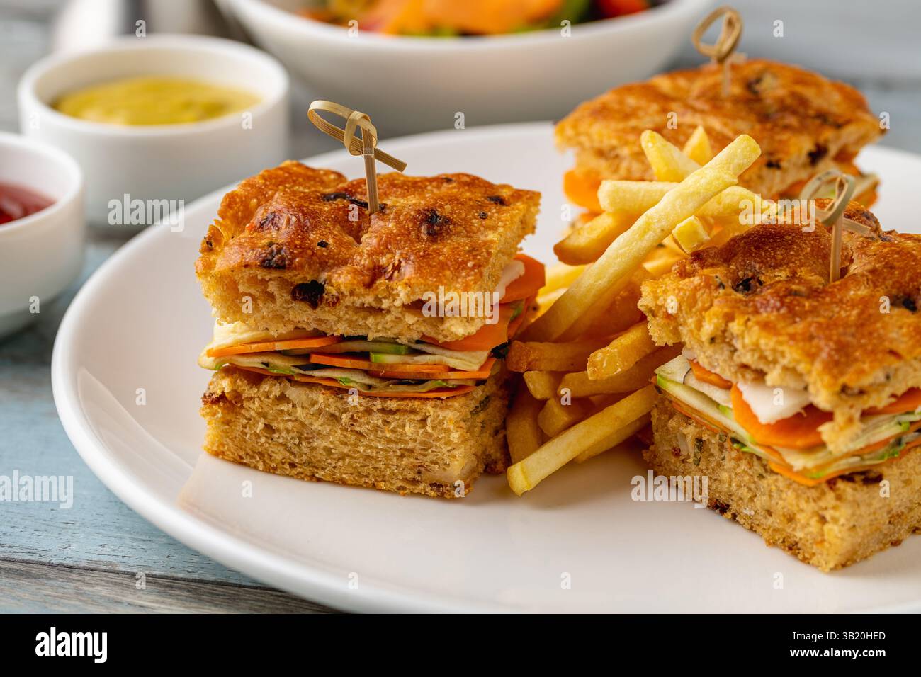 Panini da buongustai quadrati con patatine fritte serviti su un piatto bianco Foto Stock