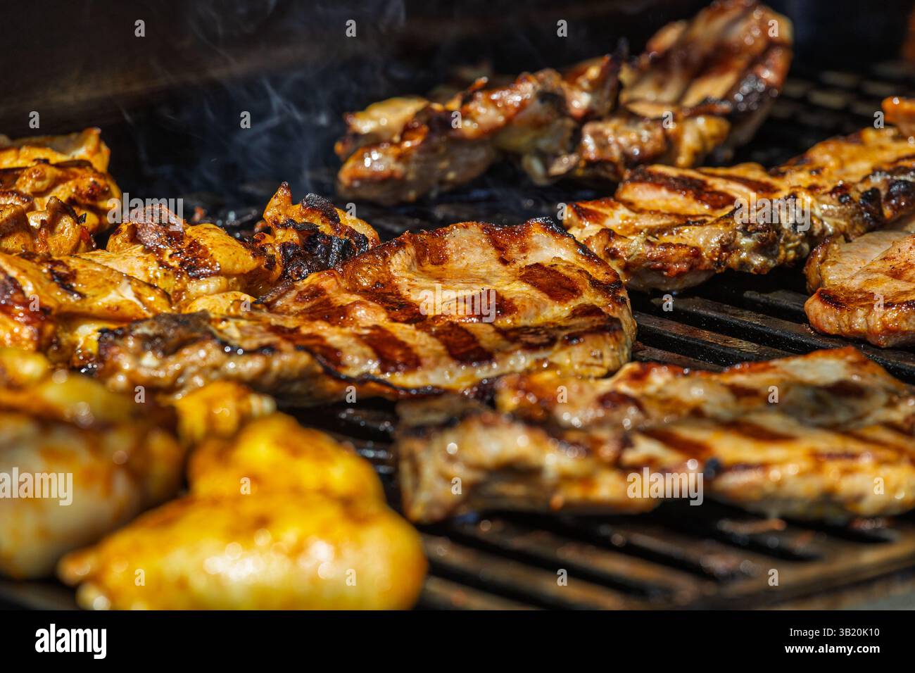 Succosi pezzi di carne marinata grigliati alla perfezione su barbecue all'aperto con lievitazione del fumo, creando una consistenza dorata e deliziosa in bocca Foto Stock