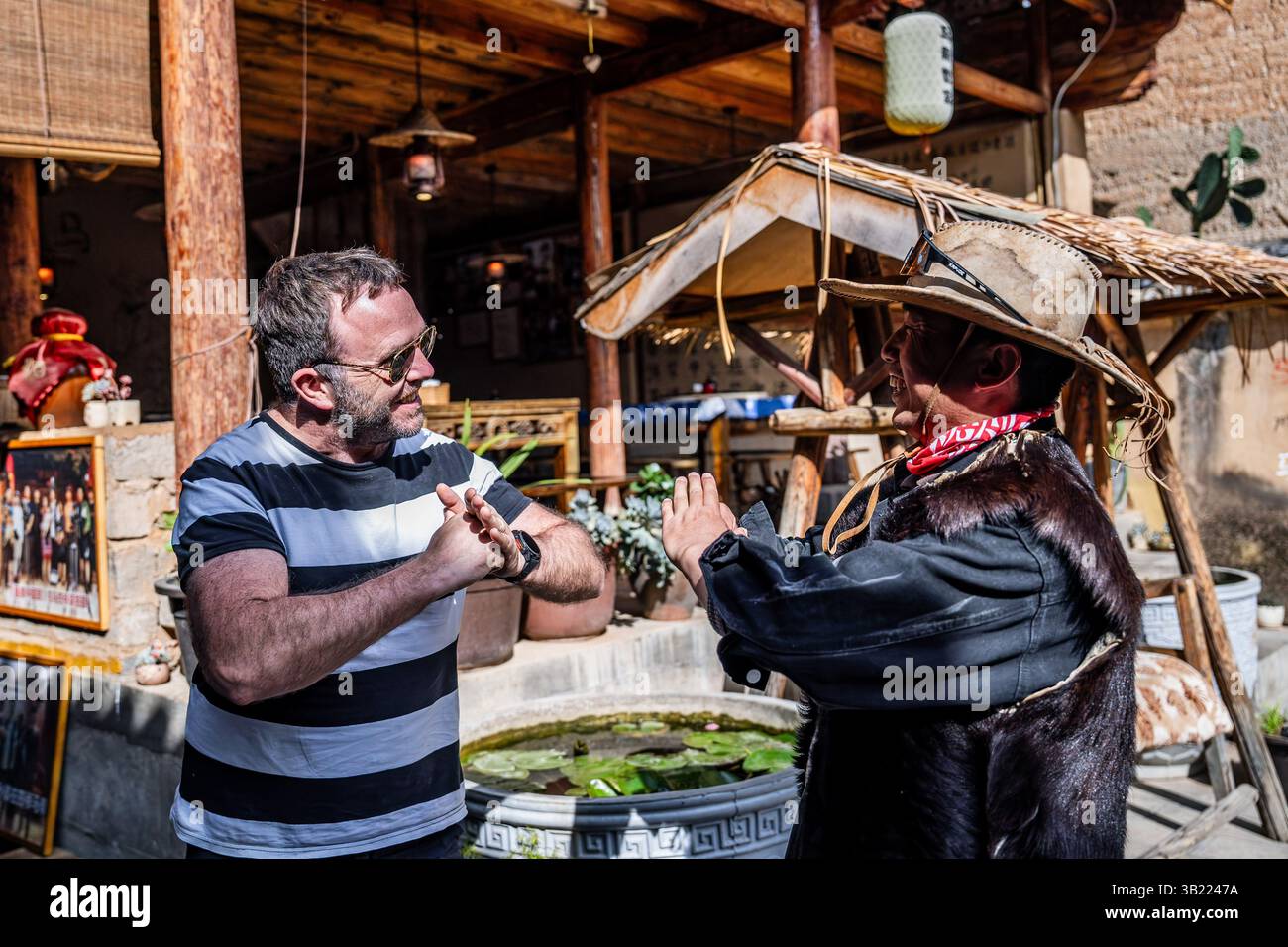 (250427) -- KUNMING, 27 aprile 2025 (Xinhua) -- Yang Siyun (R), un discendente di operatori locali di treni a cavalli, saluta un turista straniero al villaggio di Sideng della città di Shaxi, contea di Jianchuan, provincia dello Yunnan della Cina sud-occidentale, 19 aprile 2025. Una remota città nella contea di Jianchuan, Shaxi era un tempo un importante centro commerciale per tè, erbe, sete e sale sull'antica Tea Horse Road, una via commerciale che risale alla dinastia Tang (618-907). Tuttavia, il centro commerciale alla fine del XIX secolo vide un declino perché era lontano dalle moderne strade arteriose emergenti e da altri mezzi di trasporto Foto Stock
