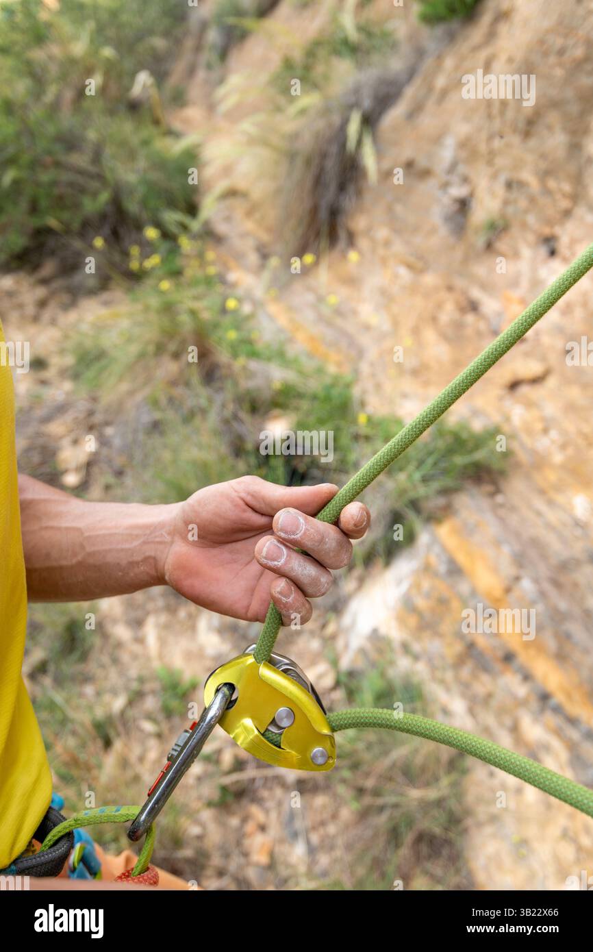Primo piano di un alpinista che indossa l'attrezzatura di sicurezza durante l'arrampicata in montagna - foto di scorta Foto Stock