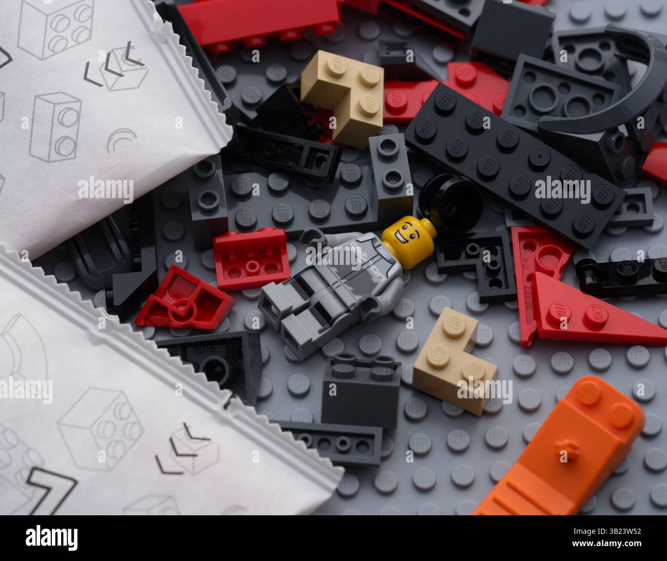 Tambov, Federazione Russa - 22 giugno 2024 Lego blocchi, mattoni, pezzi, minifigure, separatore di mattoni e sacchetti di carta con pezzi Lego su una base grigia Foto Stock