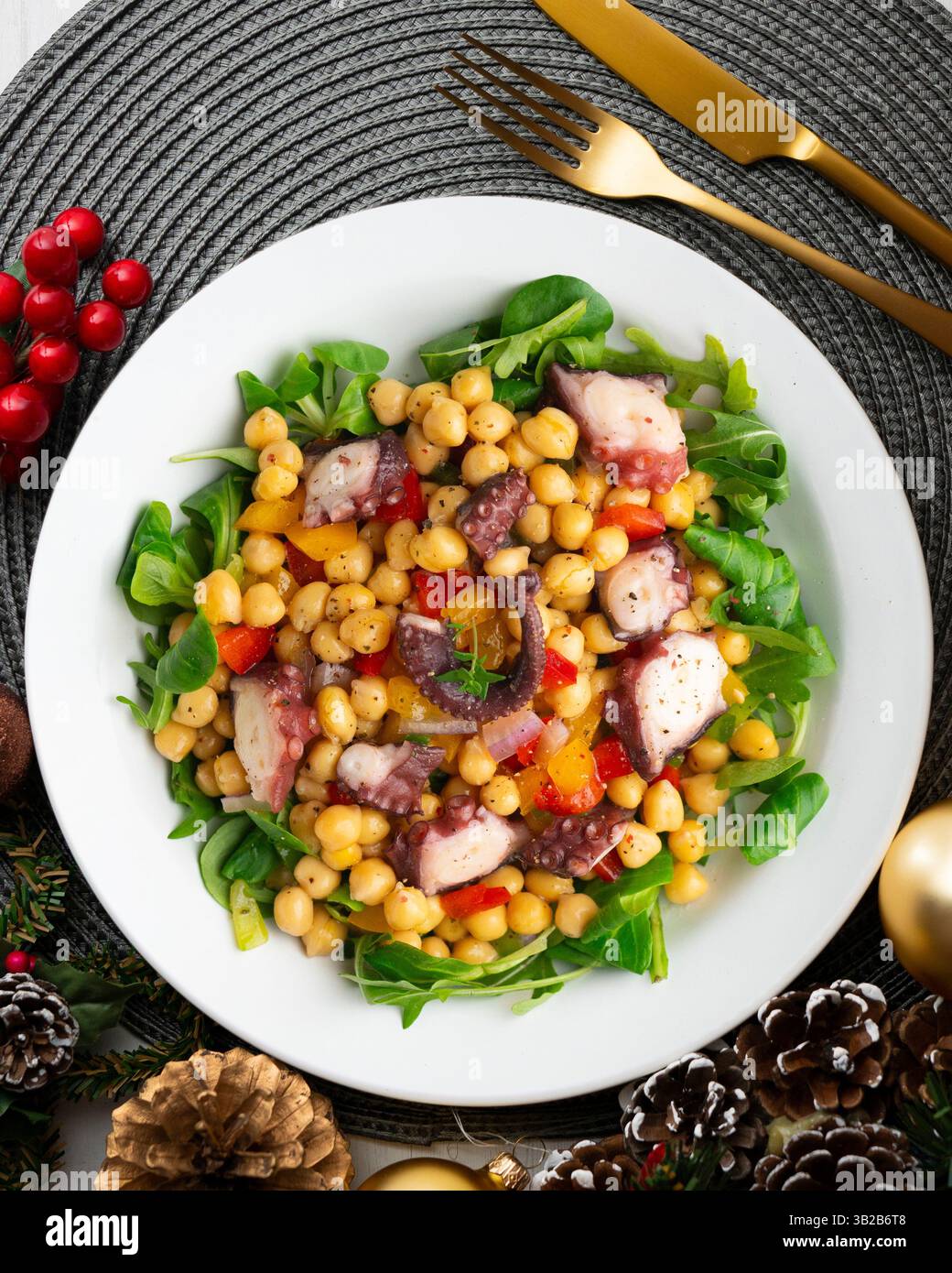 Salpicon de pulpo. Insalata di polpo con ceci, rucola e verdure. Tavolo con vista dall'alto e decorazioni natalizie. Foto Stock