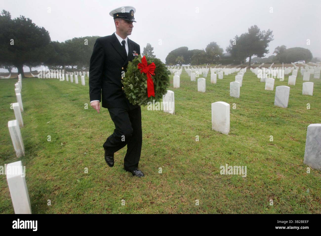 12 dicembre 2009 - San Diego, California, Messico - 12 dicembre 2009,- San Diego, CA,- 100 corone sono state posizionate al ft. Rosecrans National Cemetery come parte del programma Wreath Across America. Diverse organizzazioni locali e rami dell'esercito sono stati rappresentati durante la cerimonia che è stata abbreviata con la pioggia. Il sottufficiale della USN Alfred Dougherty portò una corona da collocare su una delle tombe del cimitero. (John Gibbins/Union-Tribune) foto obbligatoria Credit:JOHN GIBBINS/Union-Tribune/ZUMA press (immagine di credito: © The San Diego Union-Tribune/ZUMApress.com) Foto Stock