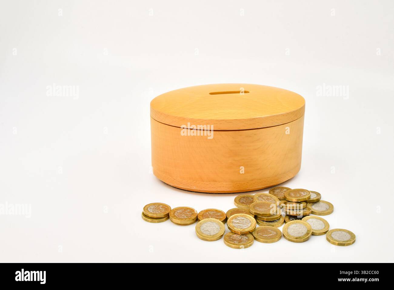Monete da una sterlina accanto a una cassetta di legno. Concetto di risparmio. Niente persone. Foto Stock