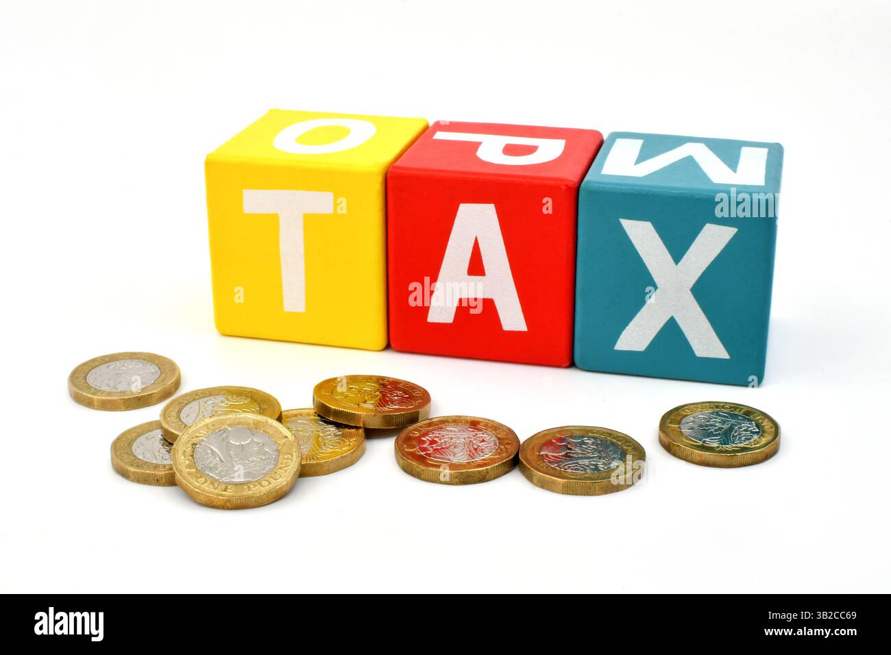 Monete inglesi da una sterlina davanti a blocchi di legno colorati che scrivono la parola Tax isolate su un semplice sfondo bianco Foto Stock