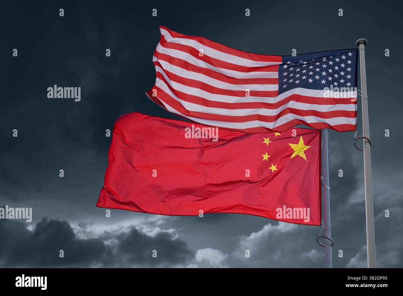 Bandiere americane e cinesi sullo sfondo di un cielo drammatico. Simbolo di guerra commerciale. Foto Stock