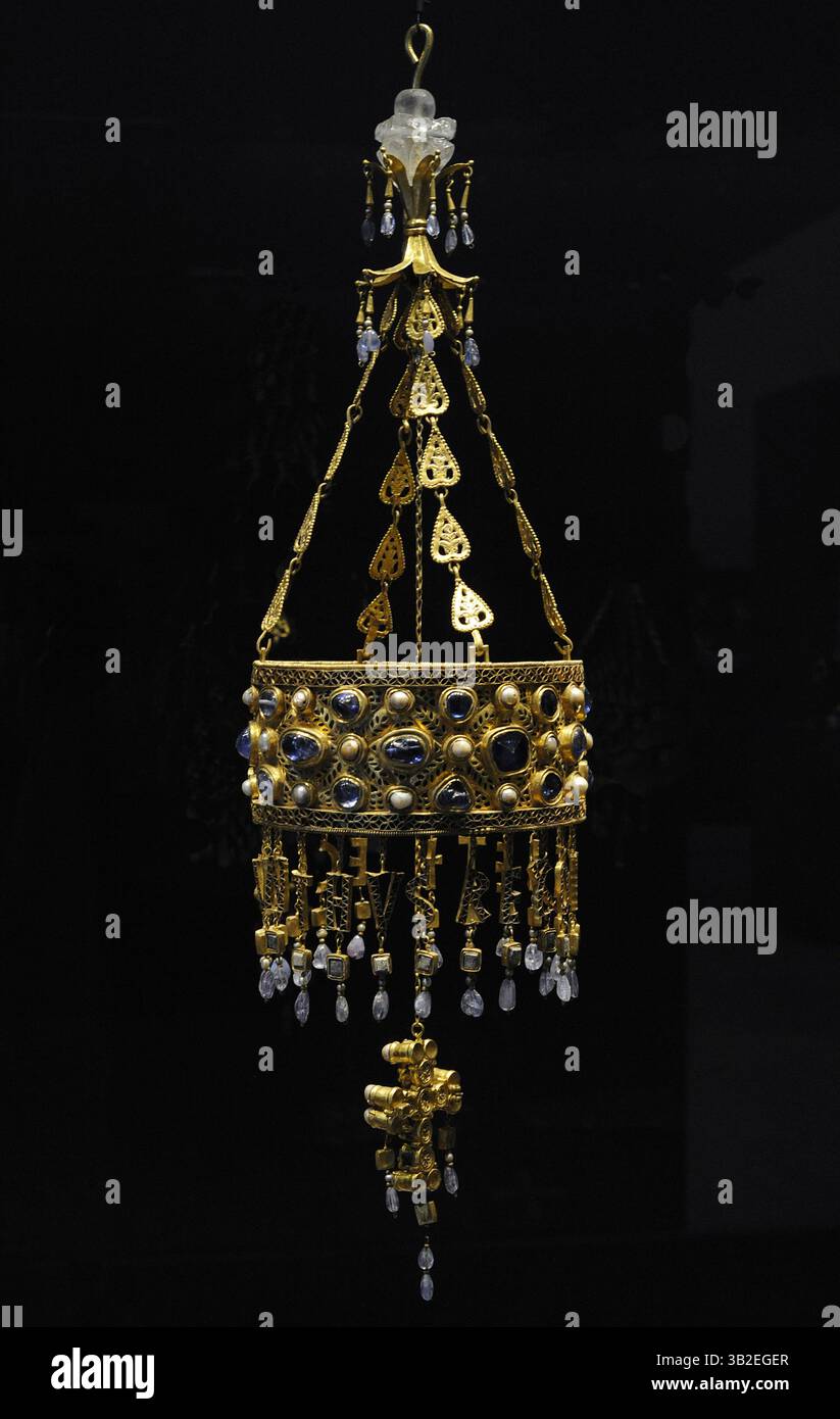 Tesoro di Guarrazar. Corona di Recceswinth. Oreficeria visigota. Datato tra il 621 e il 672 d.C. La corona fu offerta dal re visigoto Recceswinth (649-672). Il diadema è realizzato in doppio oro placcato a forma di due semicircoli articolati da cerniere. Gli zaffiri e le perle di Cabochon coprono il diadema. Maglie a catena sotto forma di foglie di pere, unite alla base di un doppio giglio bianco, coronate da un piccolo capitello di cristallo di roccia. Dal fondo del diadema appendere le lettere che compongono la dedica reale. Fu realizzato dalla corte di Toledo. Altezza: 80 cm, lunghezza o. Foto Stock