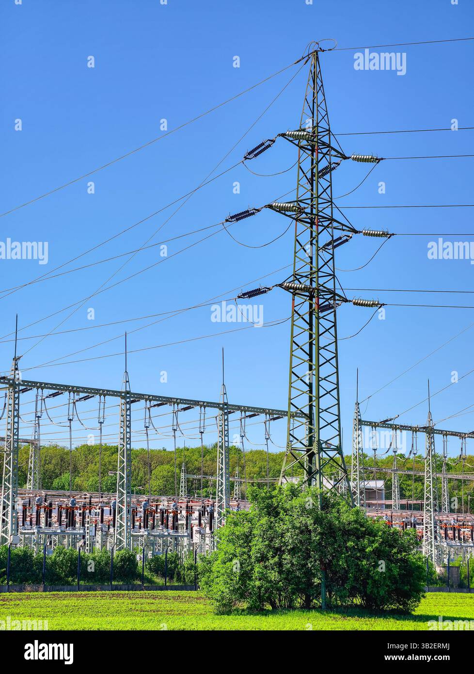 Infrastruttura di distribuzione dell'alimentazione ad alta tensione. Moderna stazione elettrica e torre di trasmissione contro il cielo azzurro. Rete di energia industriale Foto Stock