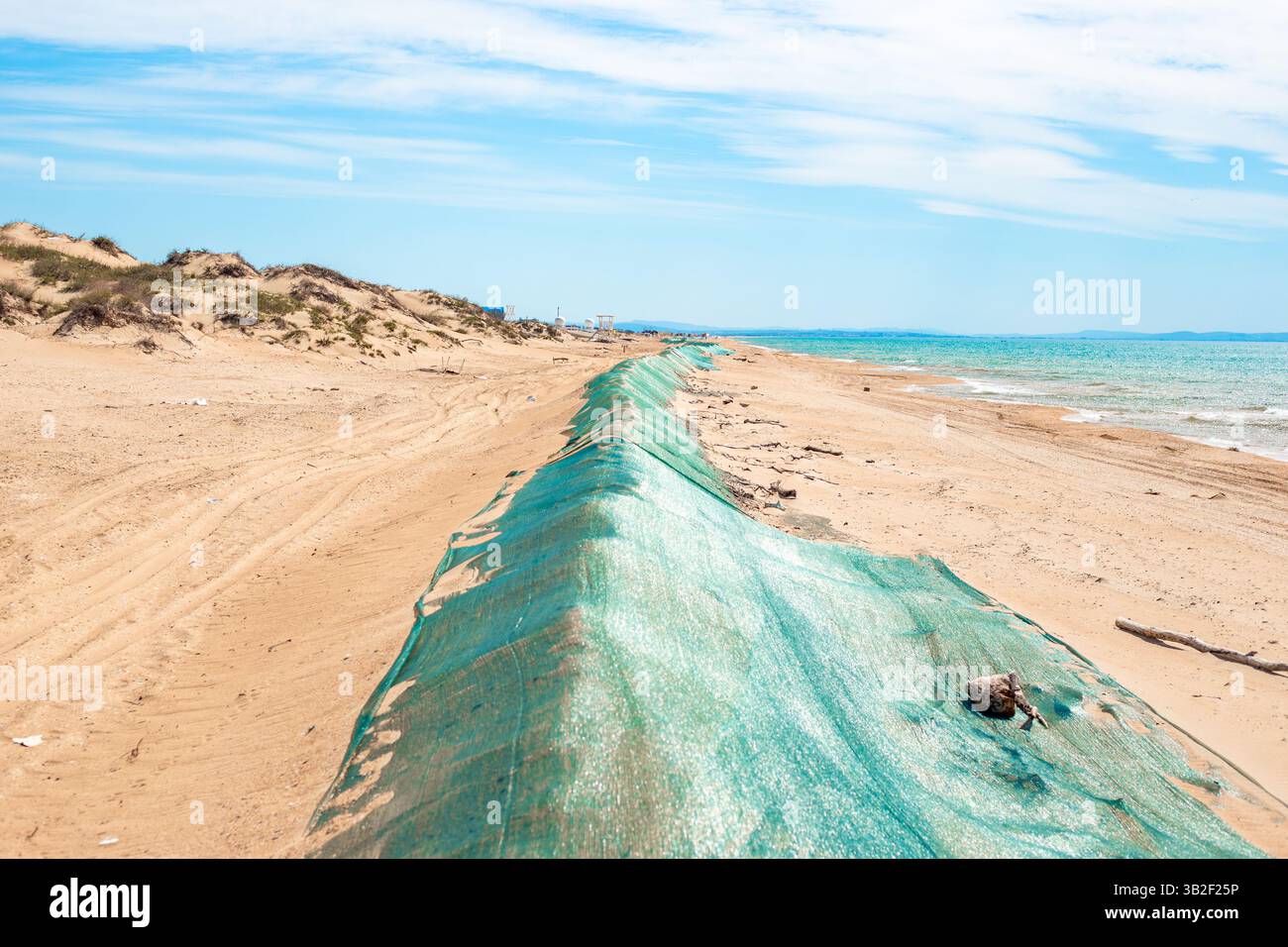 Fuoriuscita di olio combustibile in mare. Duna di sabbia di barriera, coperta da rete protettiva dall'olio combustibile gettato a terra dalle onde. Catastrofe ecologica, metodi di elim Foto Stock