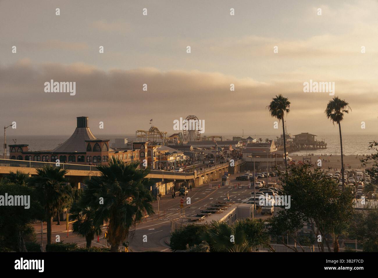 Coastal Urban Fusion - tramonto con palme, ruota panoramica e paesaggio urbano Foto Stock