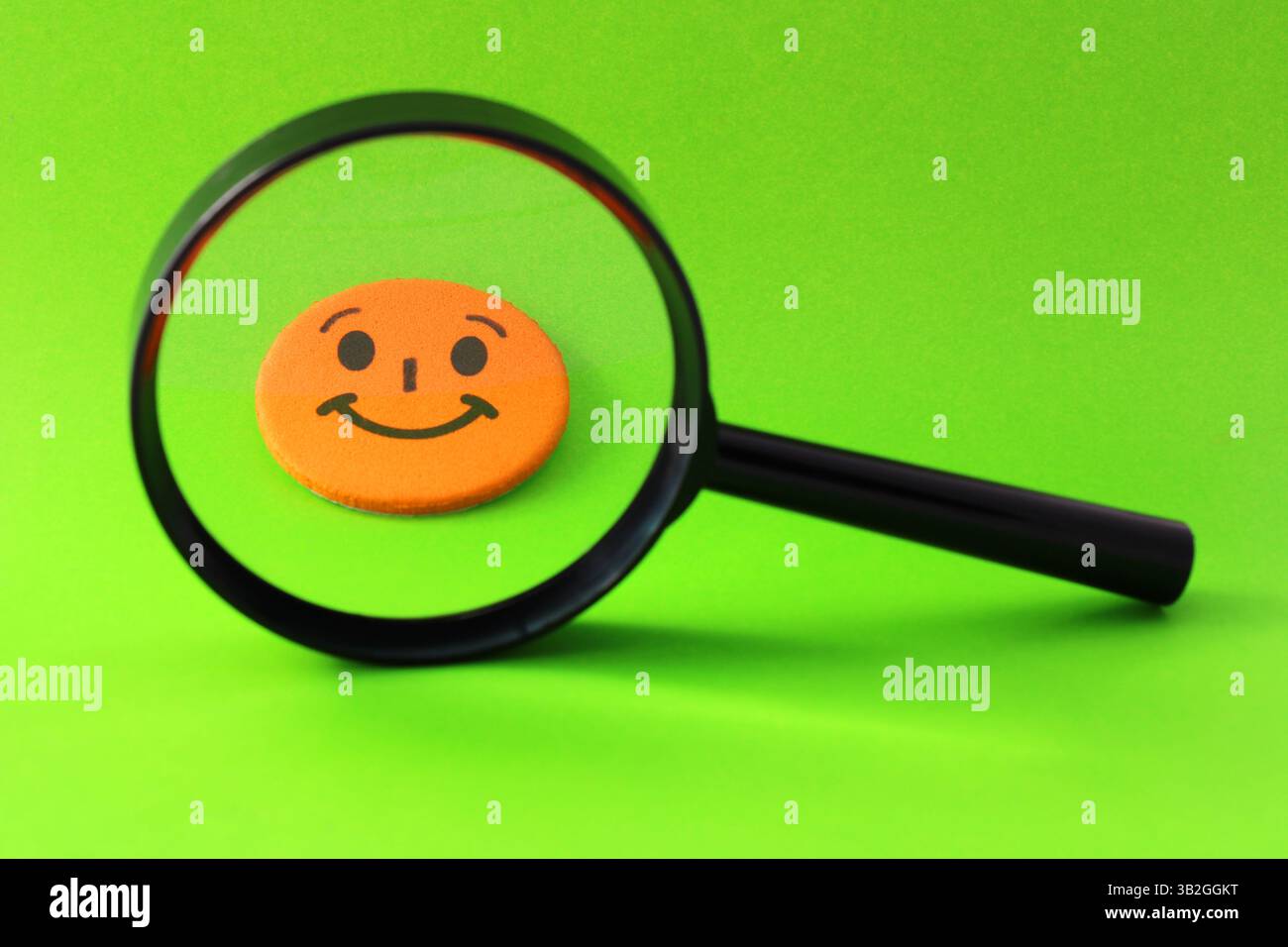 Lente d'ingrandimento per selezionare un volto felice Foto Stock