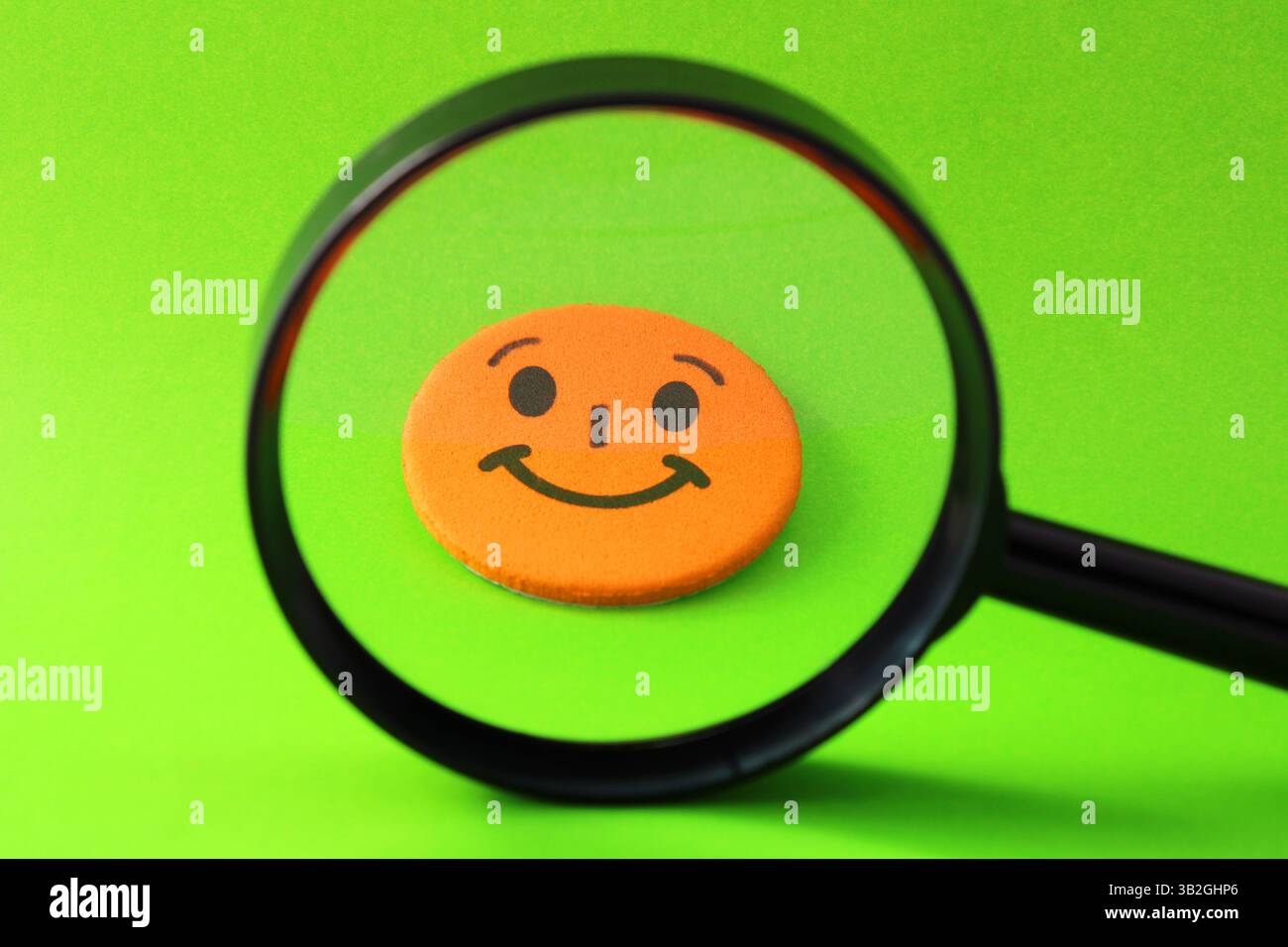 Lente d'ingrandimento selezionando un volto felice arancione Foto Stock