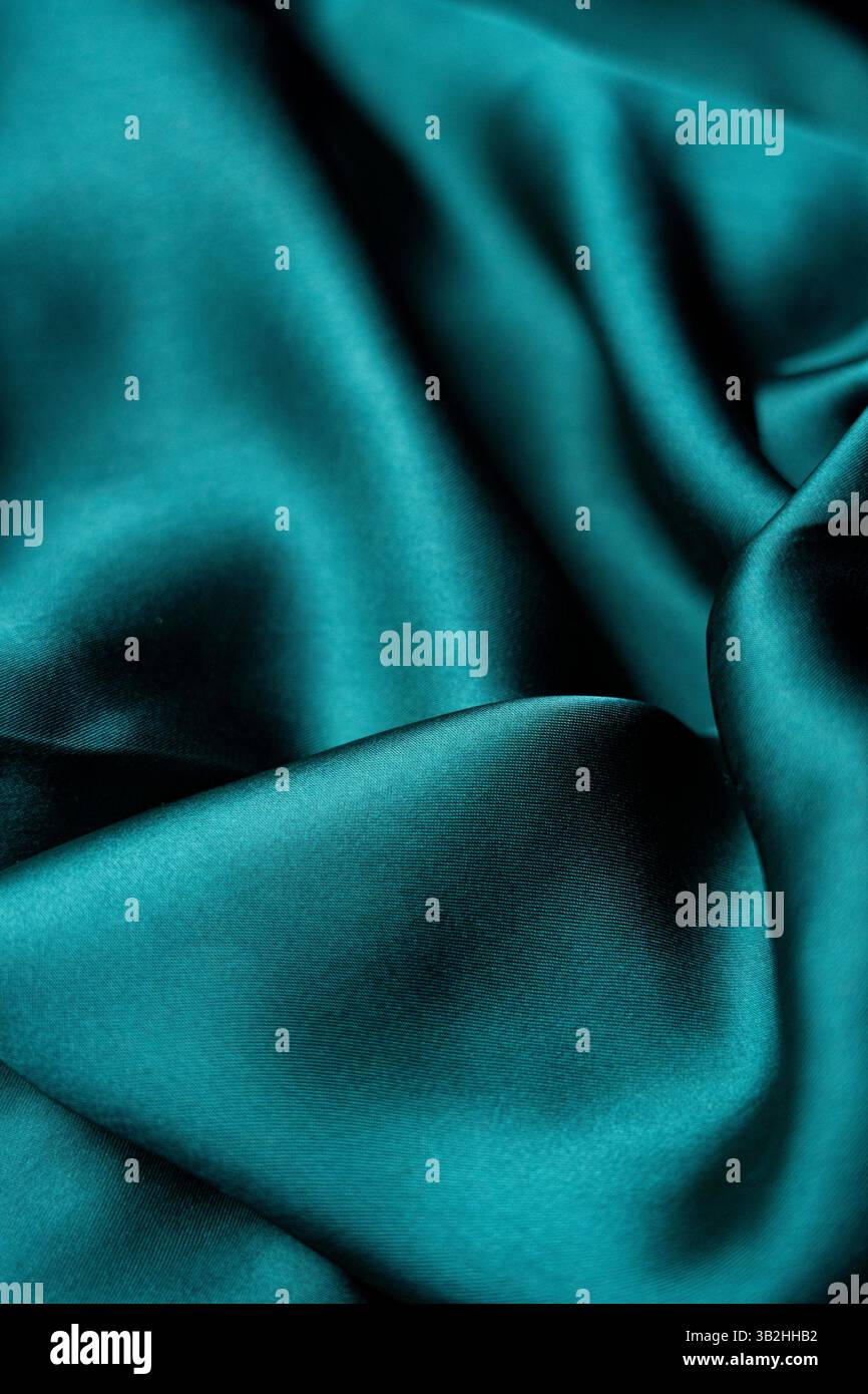 Questo tessuto in raso verde lucido è liscio e ricco di texture, perfetto per creare un'atmosfera lussuosa o per sfoggiare tessuti di alta qualità Foto Stock