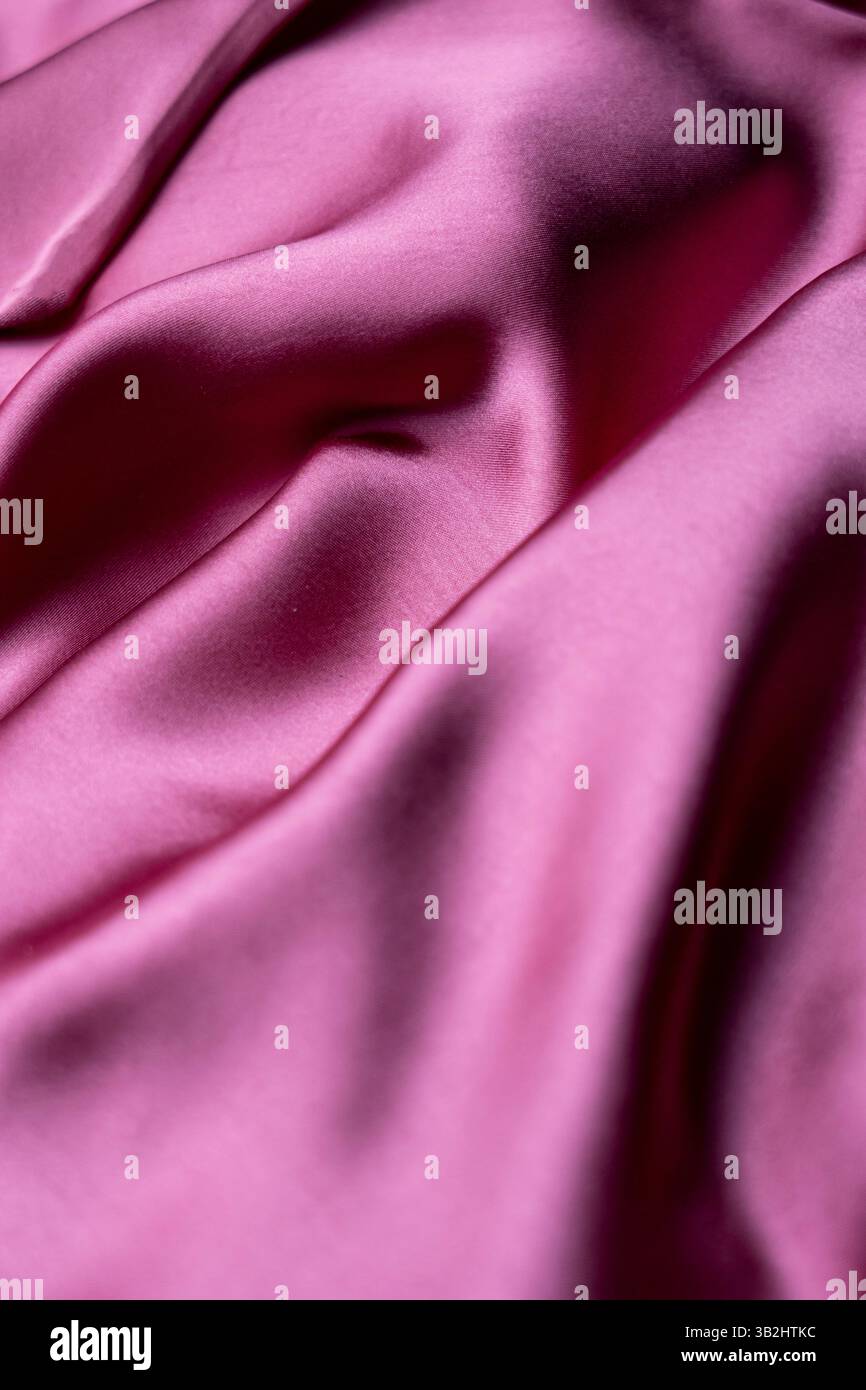 Un panno rosa chiaro delicato ed elegante che riflette la luce con una delicata lucentezza, perfetto per la moda, la fotografia o l'arredamento. Foto Stock