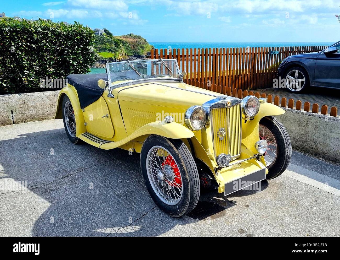 Lussuosa auto sportiva in vinage gialla da collezione in un parcheggio con il mare sullo sfondo Foto Stock