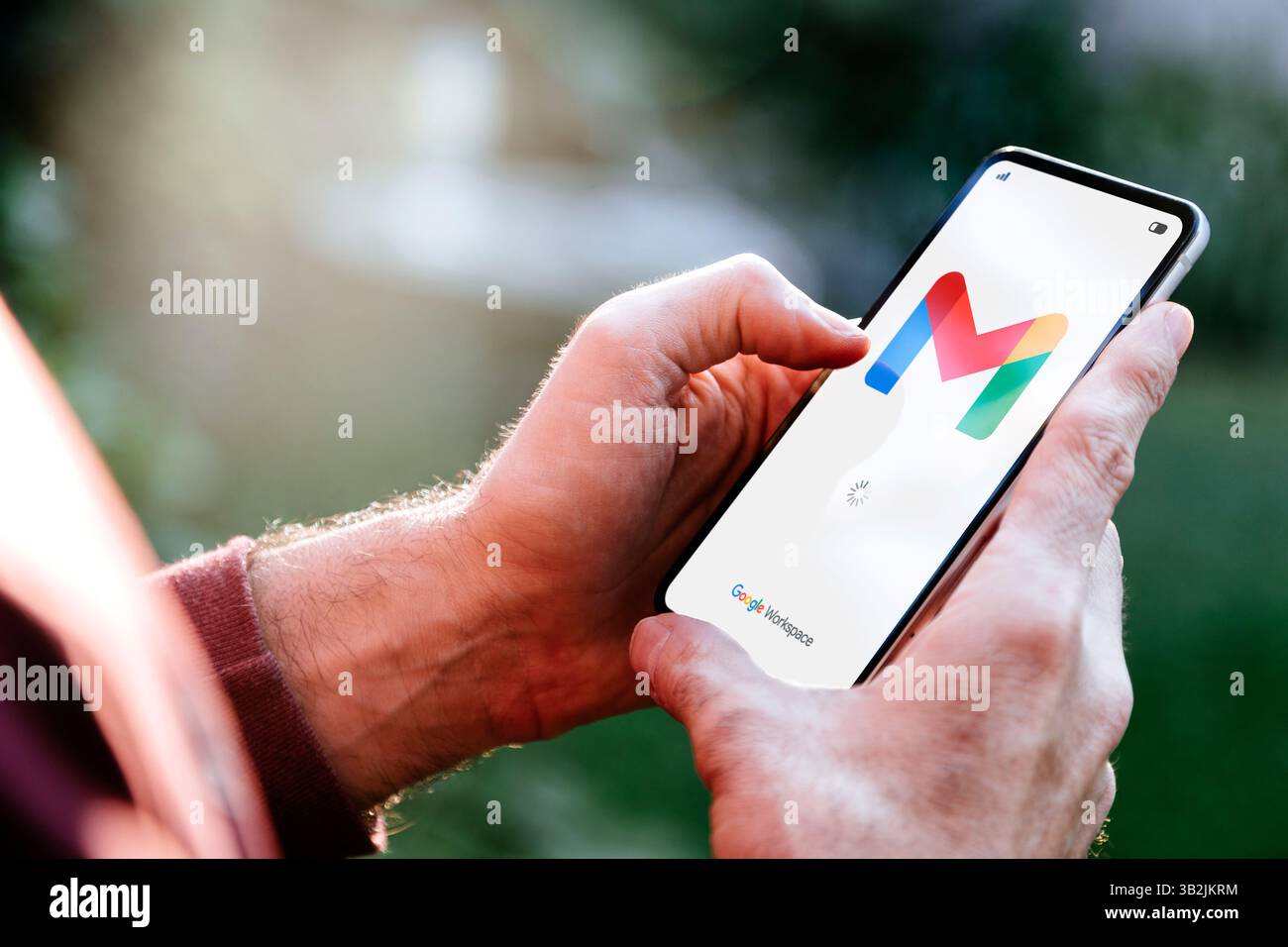 Uomo all'aperto con un telefono cellulare che apre l'app Gmail per l'e-mail di Google Workspace. ROSARIO, ARGENTINA - 22 APRILE 2025. Foto Stock
