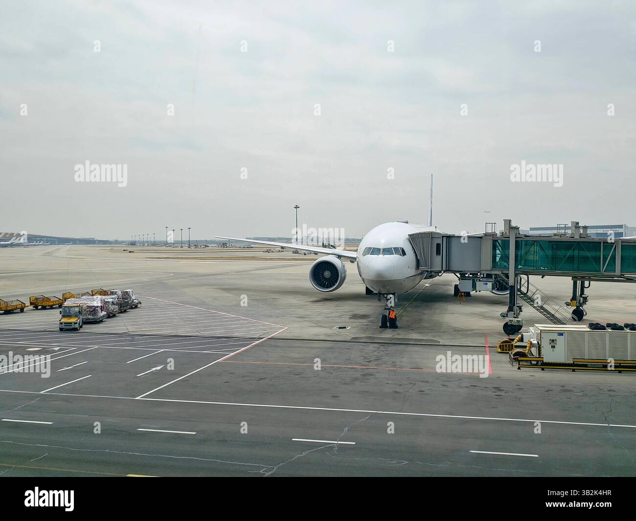 Grande jet passeggeri parcheggiato all'aeroporto internazionale di Pechino capitale, con un ponte jet collegato e un equipaggio di servizio che lavora sul telaio anteriore. Foto Stock