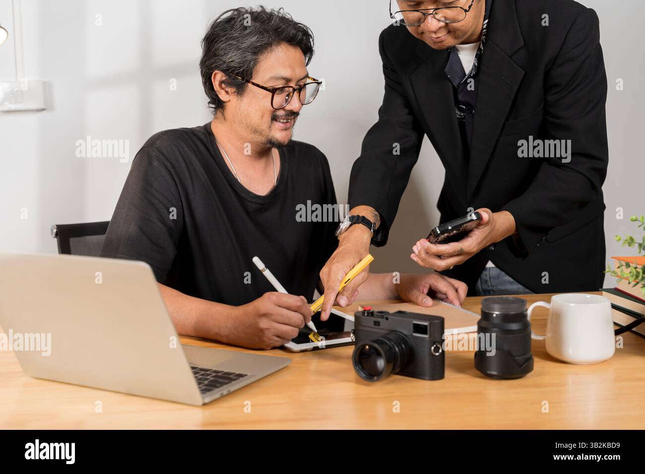 Uomo che controlla le foto con la fotocamera a casa. Fotografo che rivede il suo lavoro. Uomini che lavorano nell'ufficio editoriale. Fotografo e il suo modello che cheking pho Foto Stock
