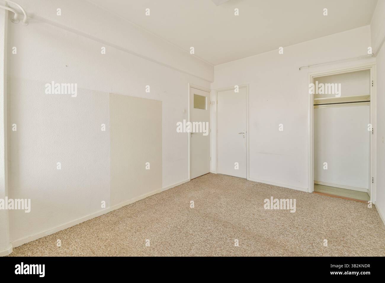 Una camera spaziosa e ordinata caratterizzata da pareti di colore chiaro, pavimento in moquette e un semplice armadio. Ideale per l'ispirazione di interior design o per inserzioni immobiliari. Foto Stock