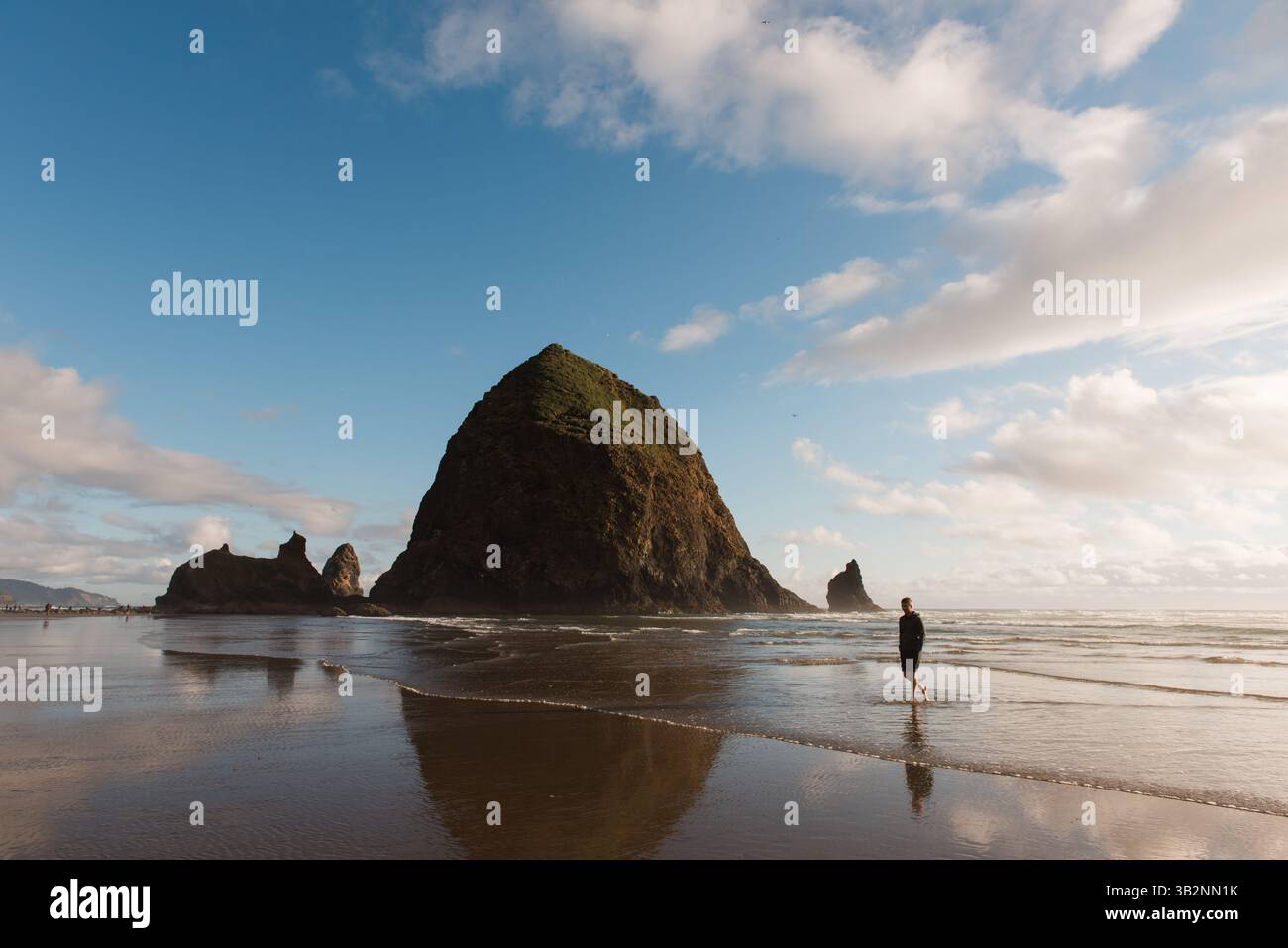 Un uomo cammina lungo la costa dell'Oregon vicino a Haystack Rock Foto Stock