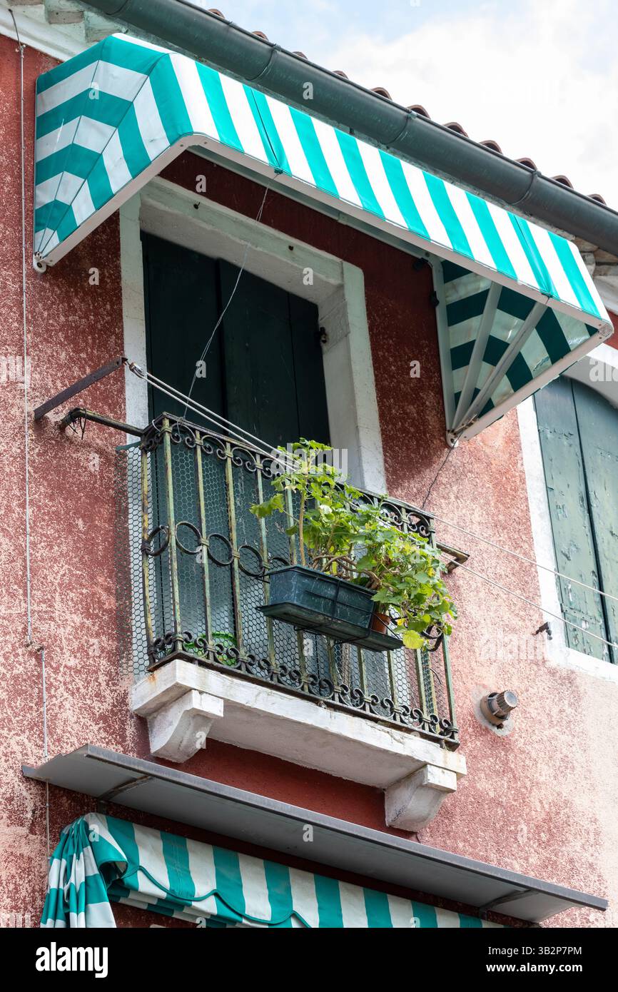 Piccolo balcone con piante verdi e tende a strisce Foto Stock