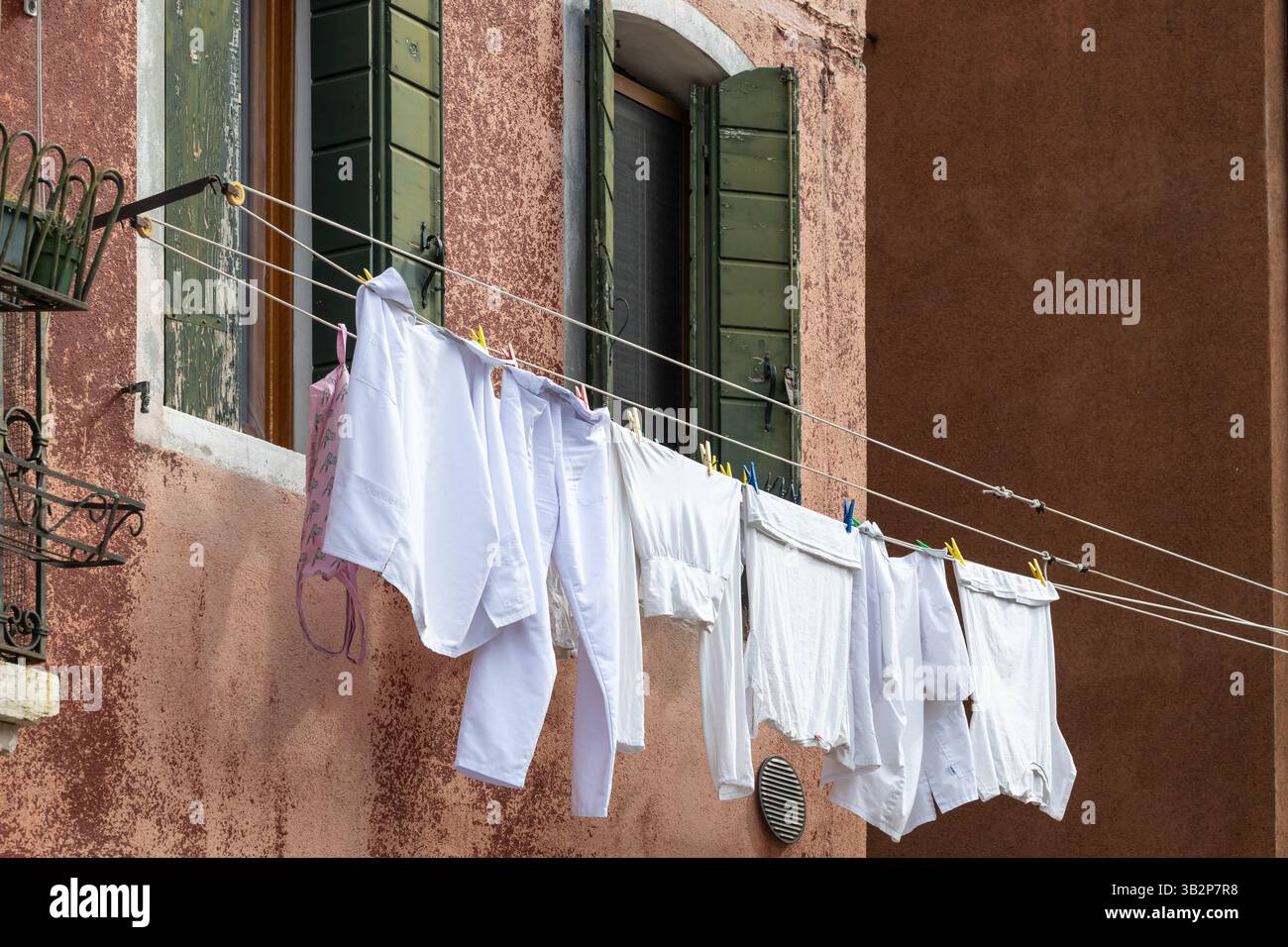Lavanderia bianca appesa all'esterno dell'edificio rustico Foto Stock