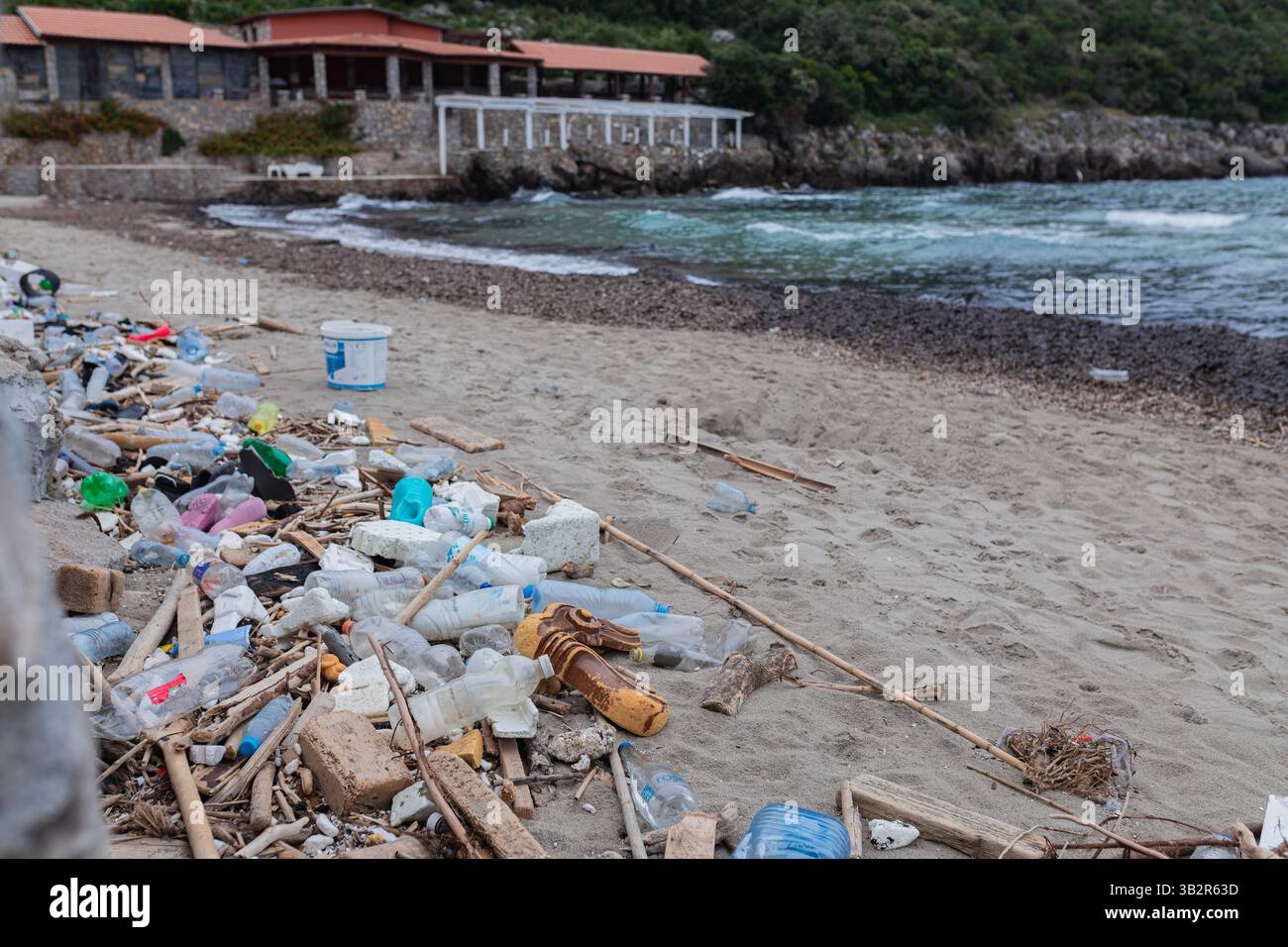 Plastica lavata e spazzatura sul bordo di una spiaggia sabbiosa Foto Stock
