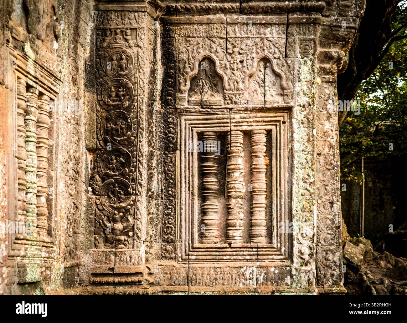 Intricate incisioni in pietra su un'antica parete del tempio, che mostrano disegni e figure dettagliate. La texture resistente agli agenti atmosferici mette in risalto l'età e la storia Foto Stock
