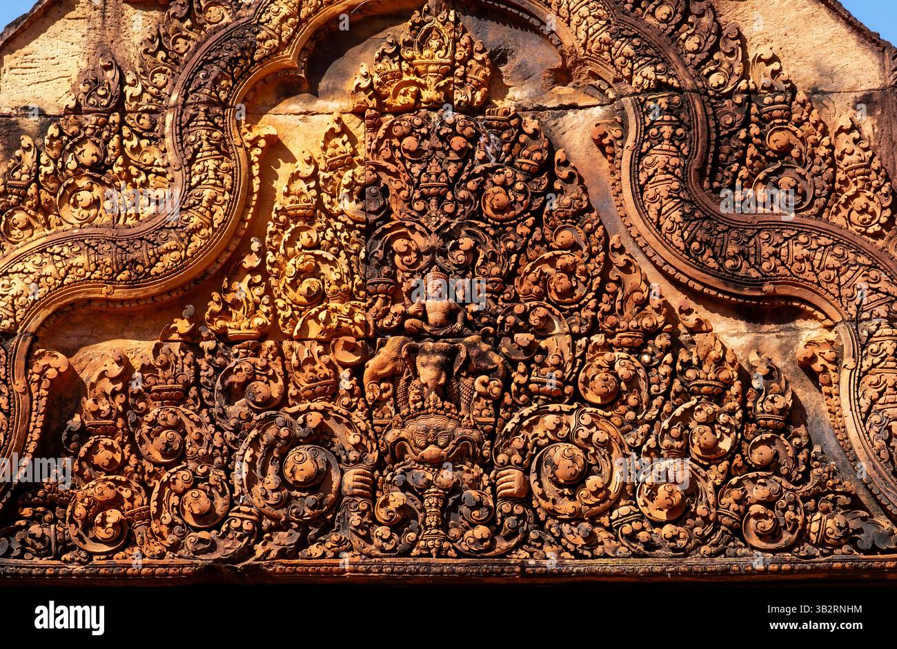 Intricate incisioni in pietra su un'antica facciata del tempio, che mostrano motivi e figure dettagliati, con una calda tonalità dorata che mette in risalto l'artigianato. Foto Stock